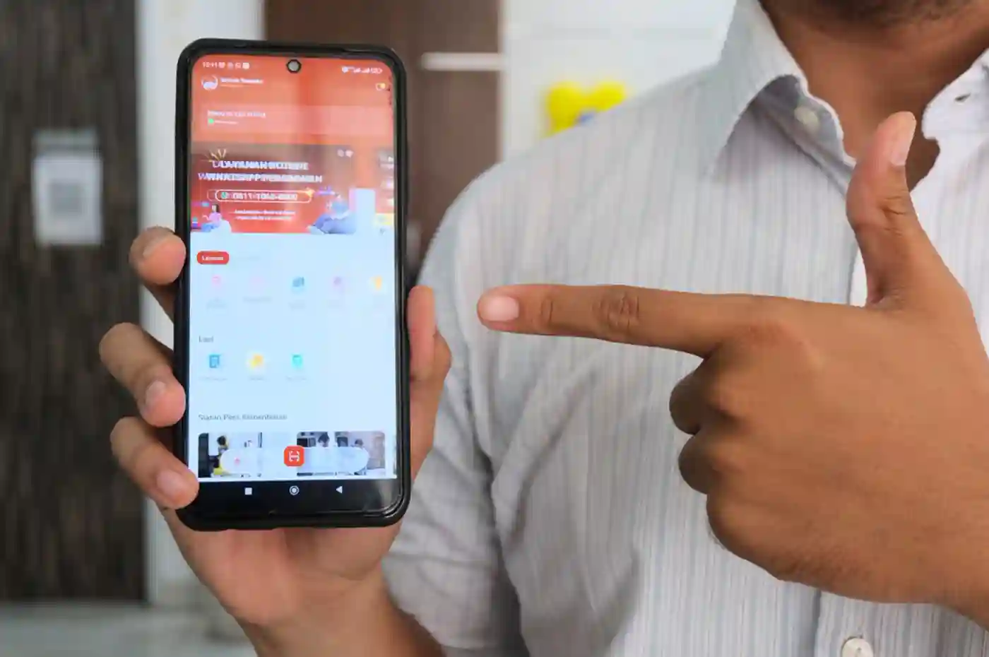 seorang pria menggunakan aplikasi sentuh tanahku di ponsel saat berada di kantor pertanahan